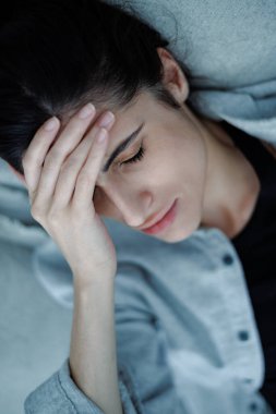 Evde yatakta yatarken alnına dokunan depresif kadın portresi