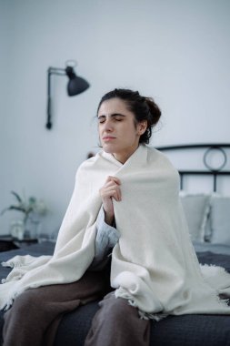 Evdeki duygusal bunalımda battaniyeyi tutan sıkıntılı kadın.