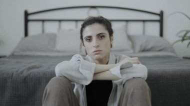 Yalnız ve depresif bir kadın yatak odasında kameraya bakıyor.