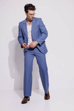 Gri arka planda poz veren mavi elbiseli esmer adam. 