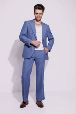 Gri arkaplanda poz veren atlet ve retro takım elbiseli modacı. 