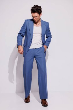 Kolsuz tişörtlü şık bir adam ve gri üzerine gölge gibi poz veren eski moda bir takım elbise. 