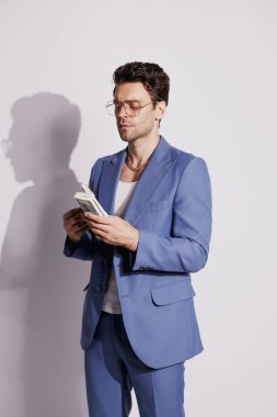 Takım elbiseli yakışıklı zengin adam Gri ve gölgeli dolarları tutuyor 