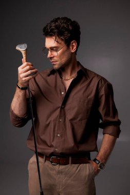 Şık tişörtlü şık esmer adam ve gözlüklü golf sopası tutan gri tenli.