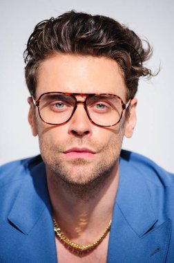 Gözlüklü ve gri ceketli şık esmer modelin portresi.