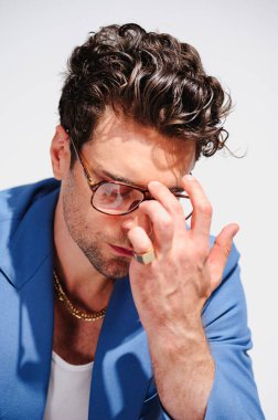 Modaya uygun esmer, mavi ceketli, altın koltuklu, gri gözlüklü adam.