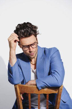 İyi giyimli gözlüklü, kolsuz tişörtlü ve mavi ceketli gri arka planda poz veren 90 'ların konsepti.