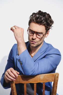 90 'lı yılların modasına uygun saç stili ve gri arka planda gözlüklü bir adam.