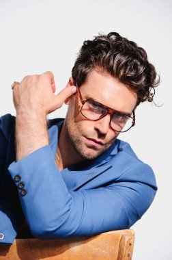 Gri renkli gözlüklü, ceketli, şık bir adamın portresi.