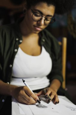 Bulanık Afrikalı Amerikalı ressam, akşam stüdyoda eskiz defterine çizim yapıyor.