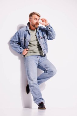 Kot ceketli, kot pantolonlu ve gözlüklü şık sakallı adam. 