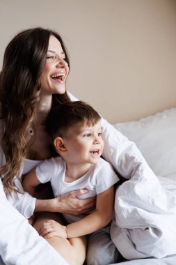 Neşeli esmer kadın, yeni yürümeye başlayan oğluna sarılıyor. 