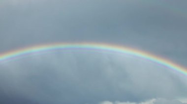 Gri gökyüzünde yağmurun ve gökkuşağının zamanı