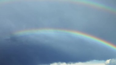 Yağmurlu gökyüzünde çifte gökkuşağının zamanı