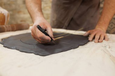 Atölyede kil kesen çömlekçinin kısmi görünümü