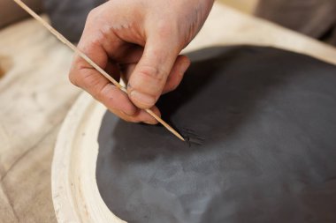 Stüdyoda çömlekçi kazıma tabağını ahşap sopayla kapat.