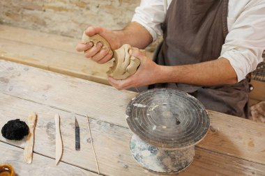 Atölyedeki araçların yanında kil alan çömlekçinin kısmi görünümü