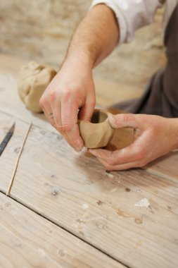 Masadaki bıçağın yanında kil şekillendiren bir zanaatkarın kısmi görüntüsü