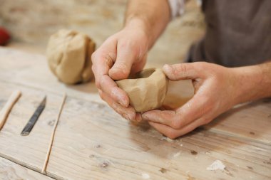 Masadaki aletlerin yanında kil bardak şekillendiren zanaatkârın kısmi görüntüsü