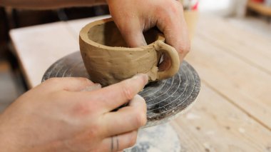 Atölyede çömlekçinin tekerlek üzerinde kil bardak yapmasını kapat