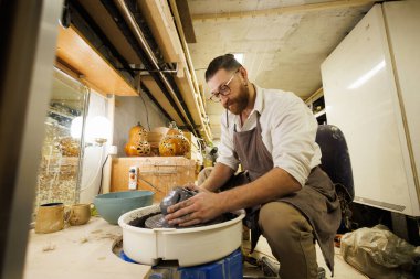 Atölyede çömlek çarkında kil şekillendiren bir zanaatkar.