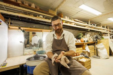 Sakallı esnaf çömlek atölyesinde el siliyor.