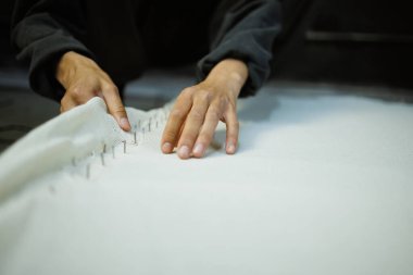 Zanaatkar kadının bir kısmı çerçeveye halı bezi çekiyor. 