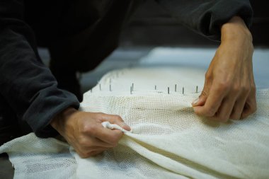 Çerçeveye halı nakışı yapan zanaatkar bir kadın.