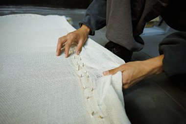 Çivili halı nakışı yapan bir zanaatkar kadın.