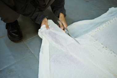 Atölyede halı bezi kesen bir kadın.