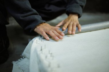 Atölyede halı için çerçeve yapan bir kadın.