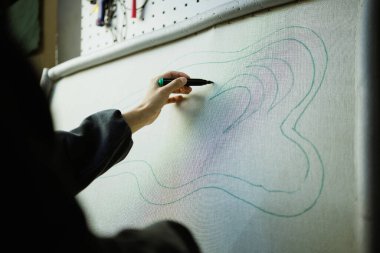 Esnaf atölyedeki halı tuvaline desen çiziyor.