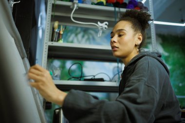 Afrikalı Amerikalı zanaatkar atölyedeki halı tuvaline resim çiziyor.