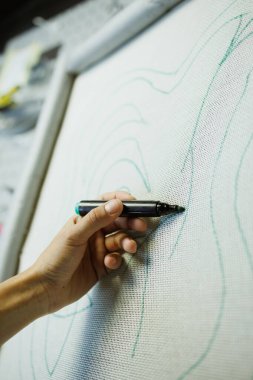 Halı nakışına çizim yapan bir kadın resmi.