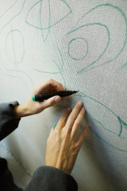 Halıyı tuvalde işaretleyen zanaatkar bir kadın.