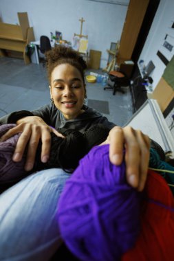 Gülümseyen Afrikalı Amerikalı zanaatkar atölyede örgü örüyor.