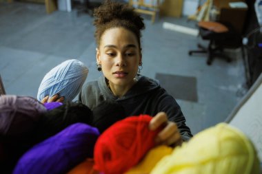 Genç Afrikalı Amerikalı zanaatkar atölyede renkli kıyafetler giyiyor.