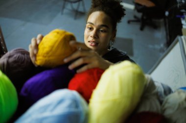 Afrikalı Amerikalı zanaatkar atölyede akrilik iplikler alıyor.