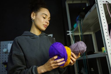 Afrikalı Amerikalı zanaatkar atölyede halı için iplik tutuyor.