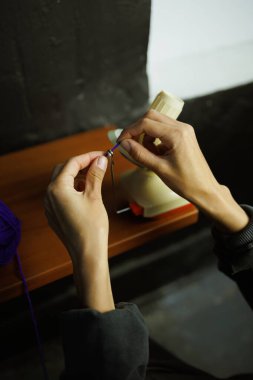 Atölyede iplik topu fırlatıcısı kullanan bir zanaatkar.