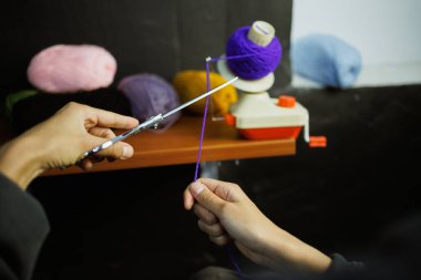 Atölyede top camında iplik kesen bir kadın.