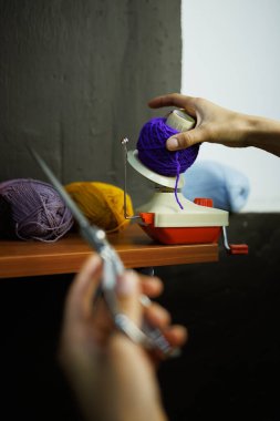 Zanaatkar kadın elindekinin bir parçası. İplik topu Winder 'ın yanında makas tutuyor.