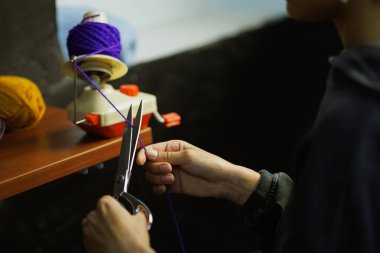 Zanaatkar kadın iplik topunu kesiyor. 