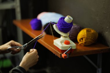 Zanaatkar kadın top camında akrilik iplik kesiyor. 