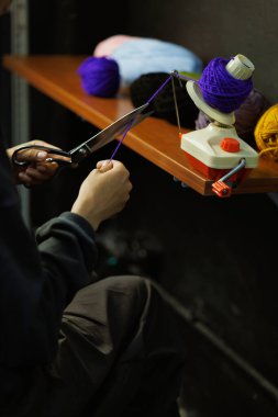 Zanaatkar kadın atölyede top camında iplik kesiyor.