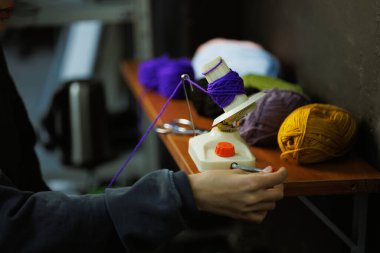 Yuvarlanan iplikler için Winder kullanan bir kadın.