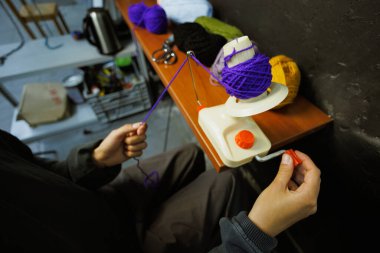 Atölyede iplik topu fırlatıcısı kullanan bir kadın.