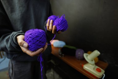 Atölyede elinde akrilik iplik tutan kadın.