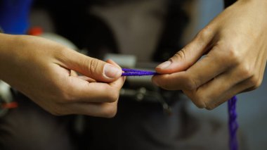 Halı dokuma makinesinin yanında iplik tutan kadın. 