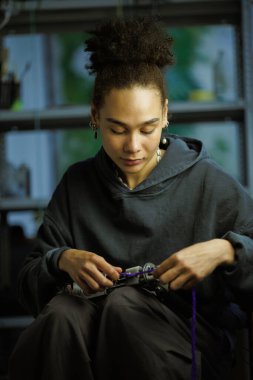 Afrikalı Amerikalı zanaatkar kadın halı temizleme tabancasıyla iplik dolduruyor. 